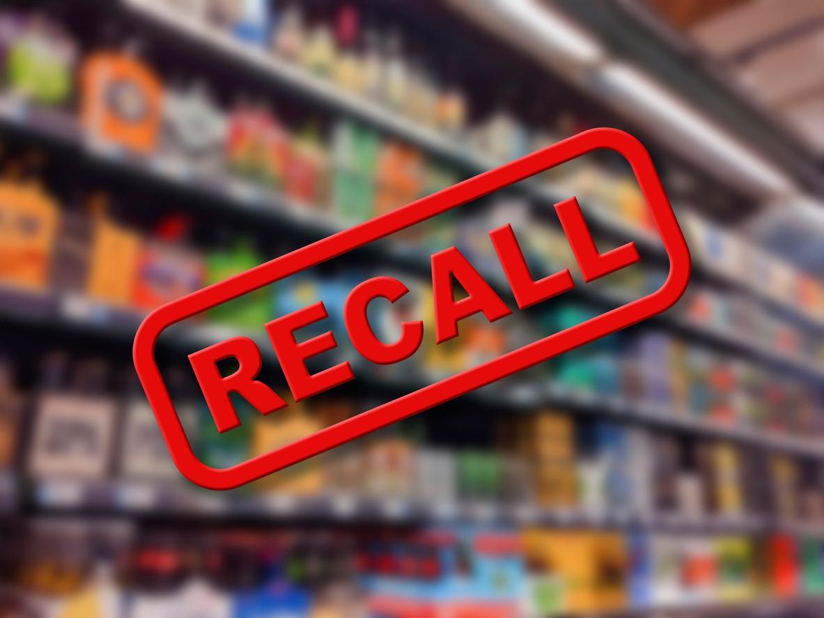 A red box with the word "recall" in all-caps is superimposed over a blurred picture of a grocery store food aisle. 