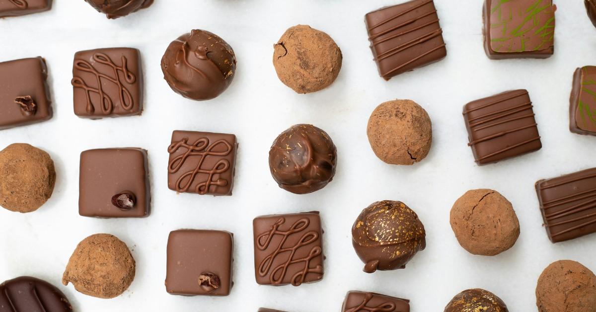 A mix of different chocolate squares and circles sits on a white plate