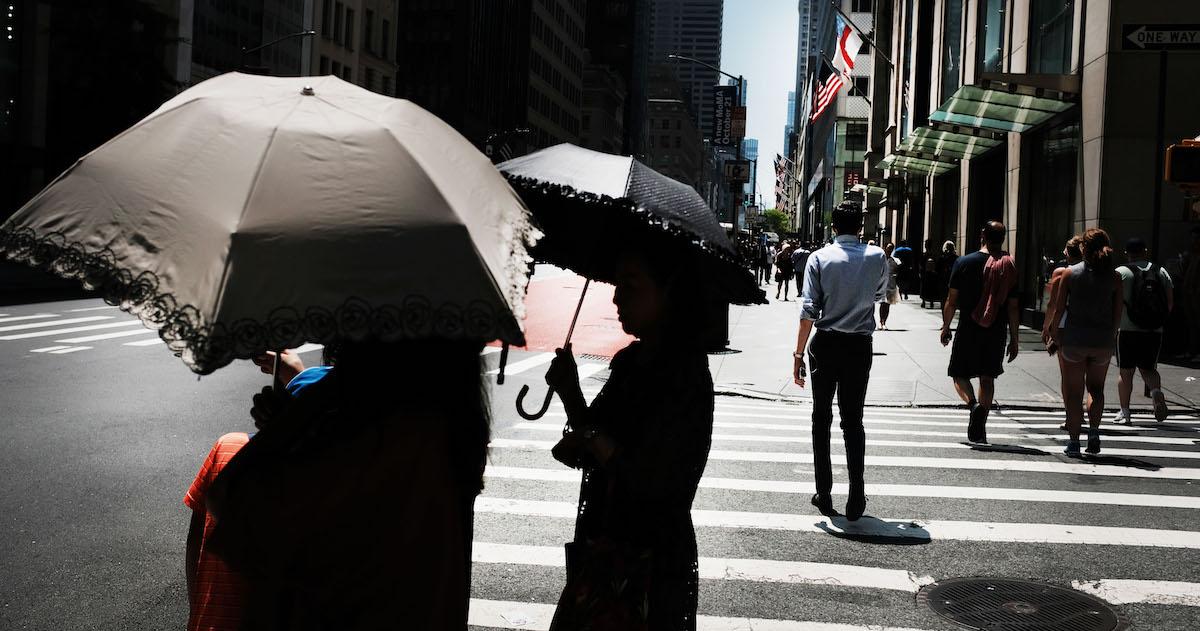 People hold umbrellas on a sunny day in New York City