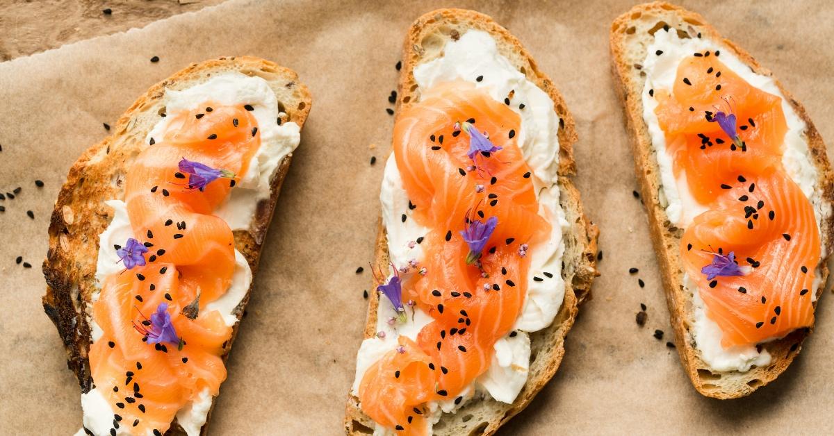 Three pieces of sliced bread with smoked salmon and sesame seeds on top. 