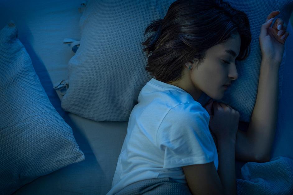 Woman sleeping on mattress at night stock photo. 