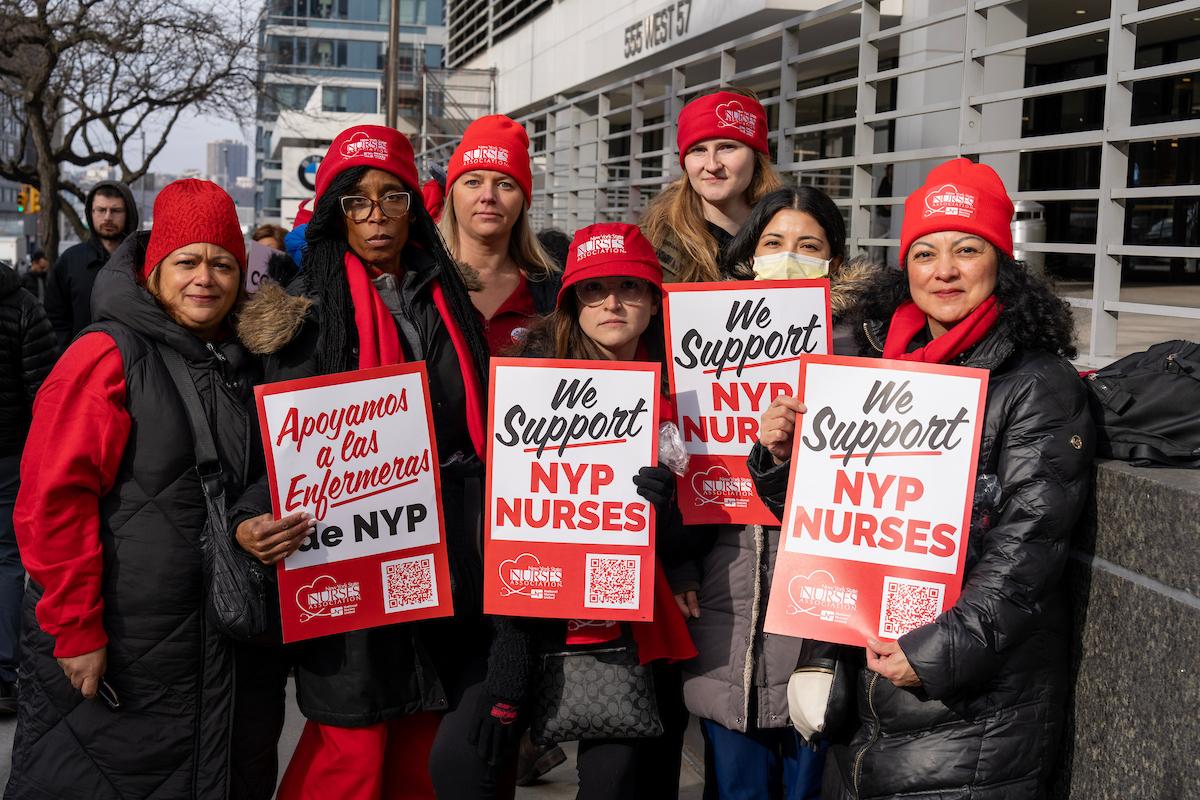 Nurses from the New York State Nurses Association are pictured holding picket signs.