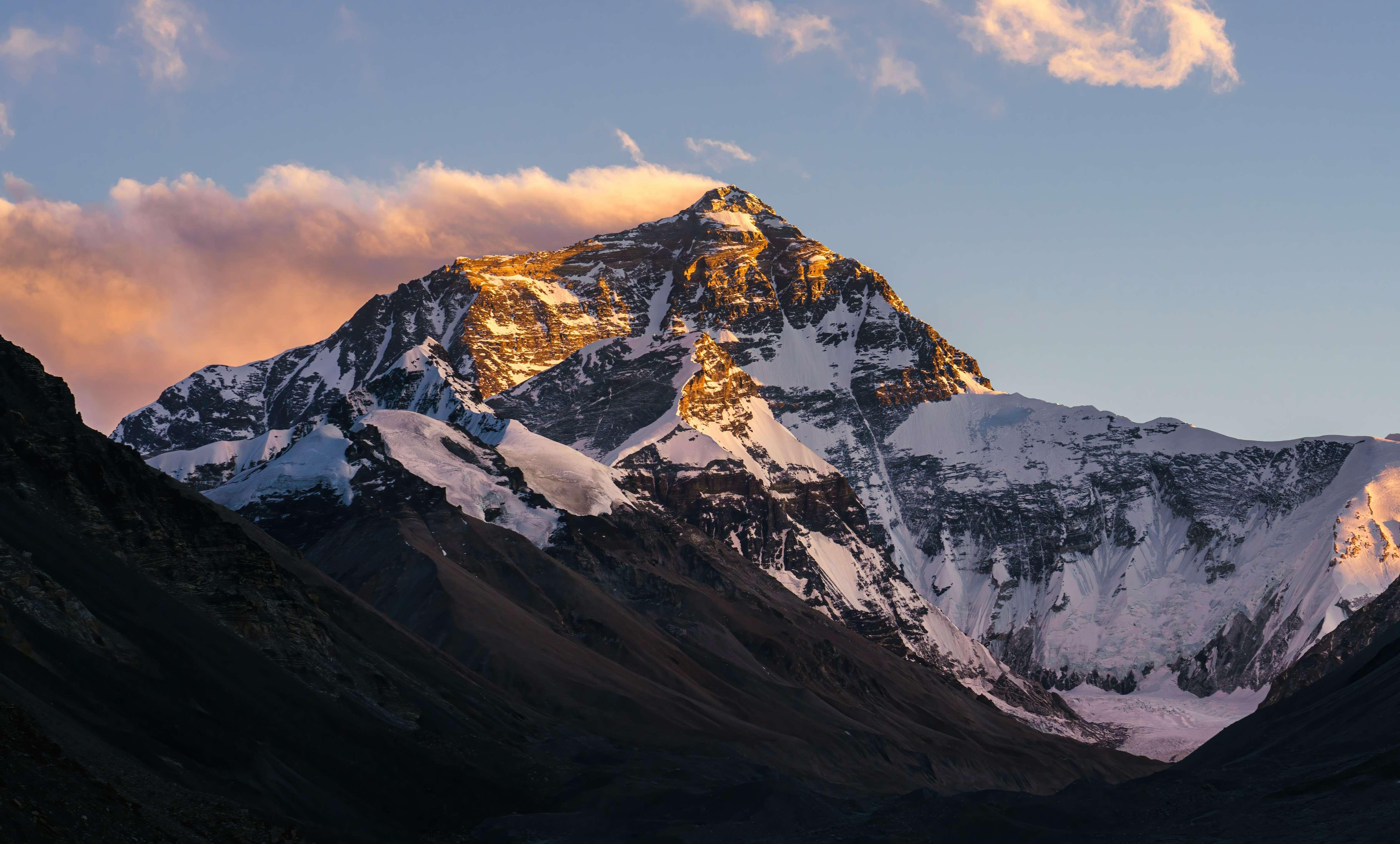 Mount Everest is pictured with snow on the mountain and the sun shining at the peak.