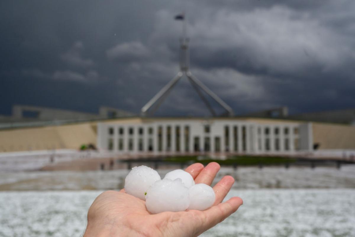 A hand holding hail about the size of golf balls