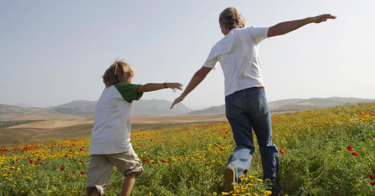 A parent and child play outside in short-sleeved, less protective clothing.