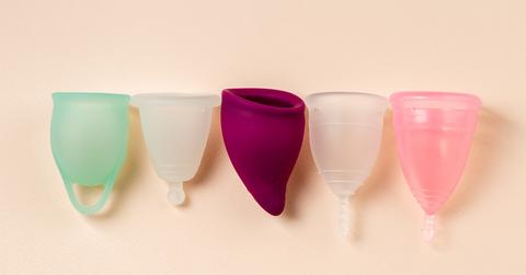 An array of five different types of menstrual cups in front of a neutral background.
