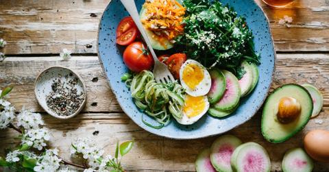 A bowl of kale, hard-boiled eggs, tomatoes, radishes and zucchini