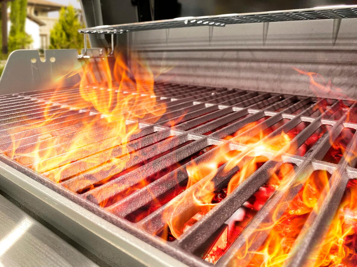 A close up of a flaming grill outside. 