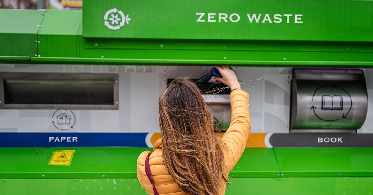 Person putting items into a recycling bin.