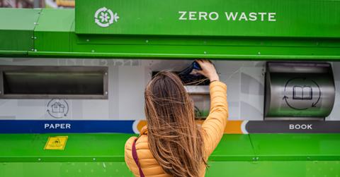 Person putting items into a recycling bin.