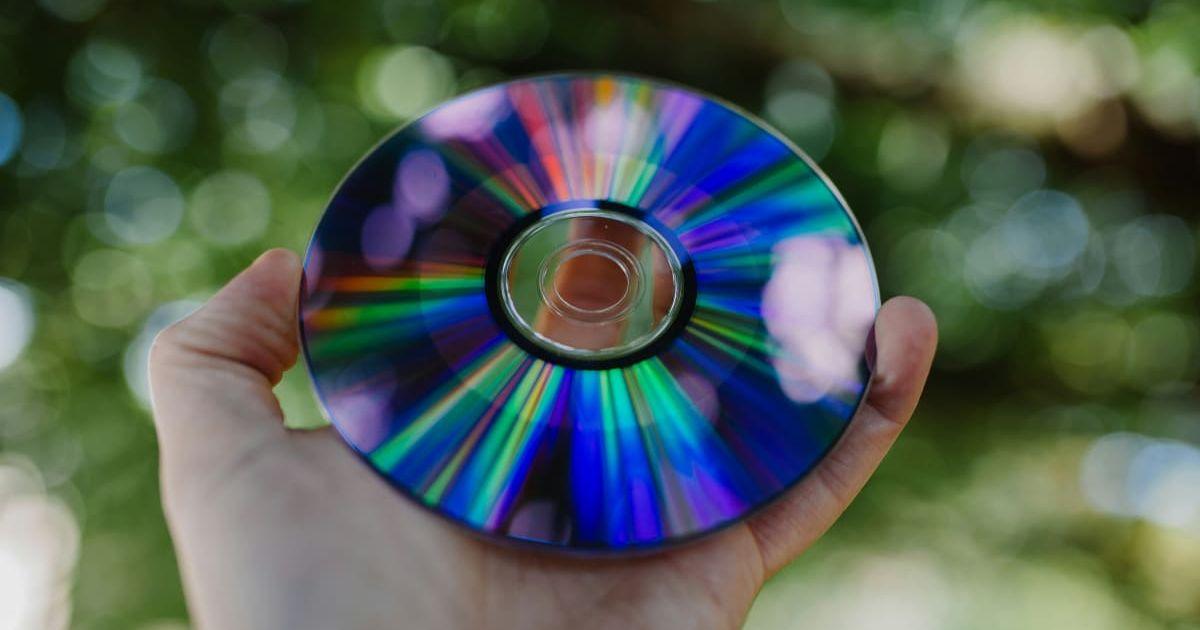 A person holding out a CD in the garden. (Representative Cover Image Source: Unsplash | Phil Hearing)