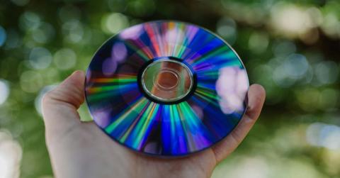 A person holding out a CD in the garden. (Representative Cover Image Source: Unsplash | Phil Hearing)