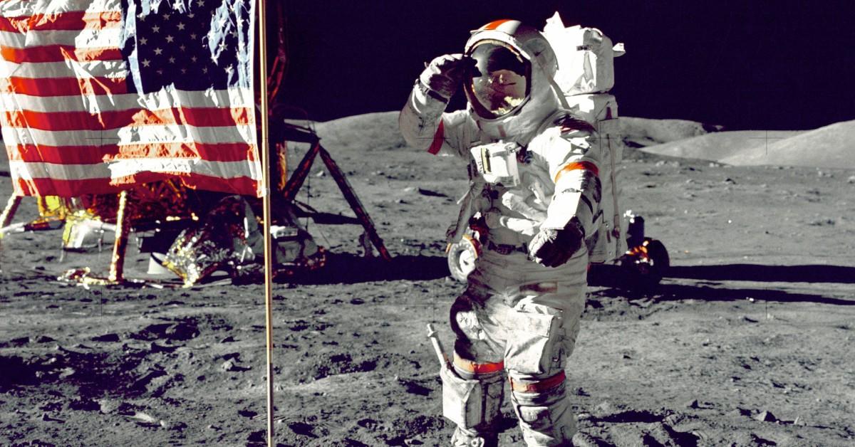 A man stands on the moon next to the U.S. flag