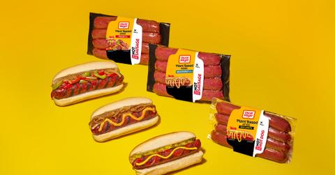 A promotional photo Oscar Mayer's plant-based sausages and hot dogs in wrappers next to the meat in buns.
