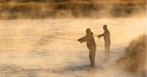 Silhouettes of visitors engaged in fishing in Yellowstone with waters shining golden in sunlight (Cover Image Source: Instagram | @YellowstoneNPS)