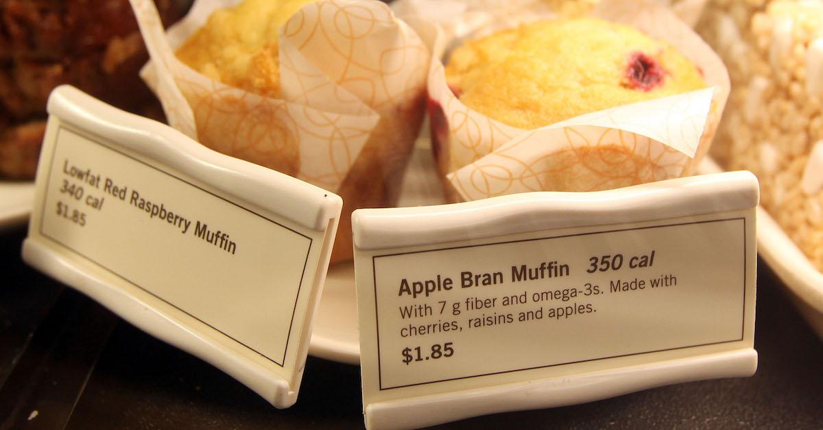 A Lowfat Red Raspberry Muffin and Apple Bran Muffin on display with signs in a Starbucks case