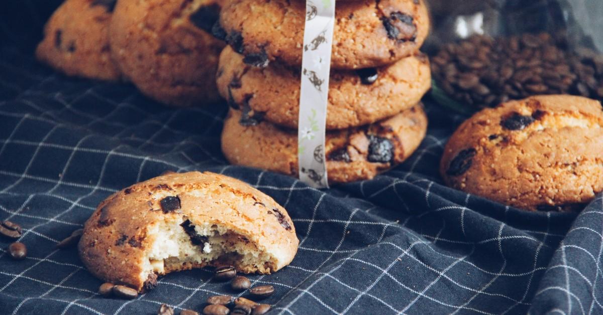 A stack of chocolate chip cookies sit on a blue and white tablecloth 