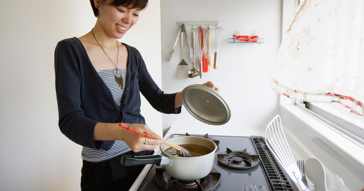 A woman stirring something in a pot on the stove.