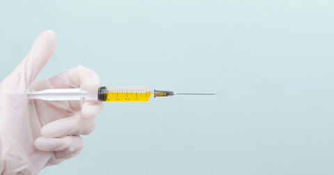 A gloved hand holds a syringe of yellow liquid