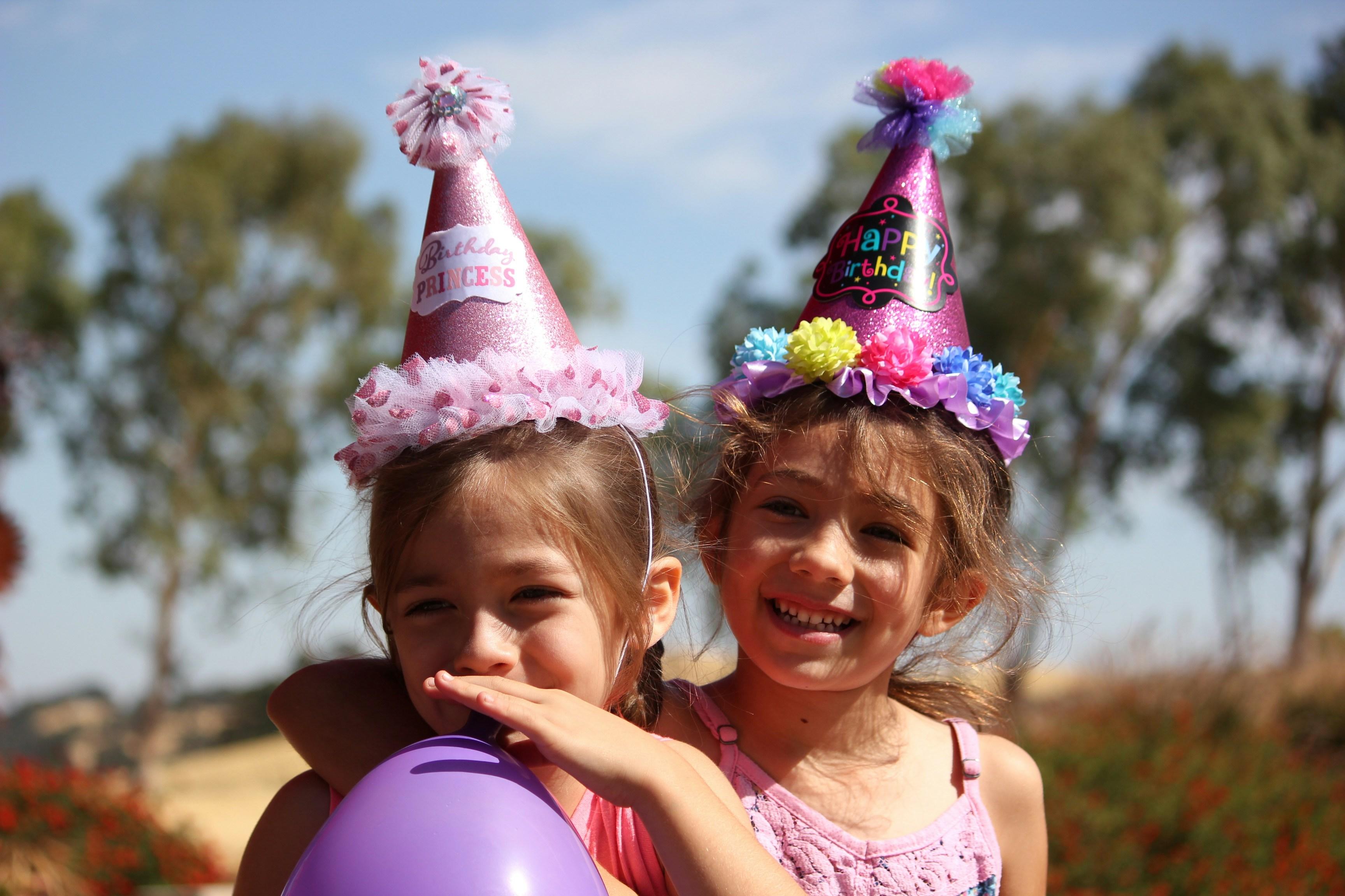 Two smiling children wear party hats during a celebration.