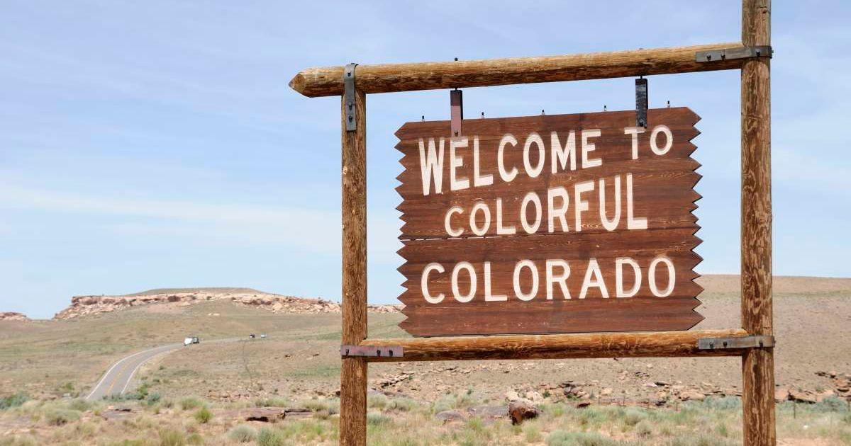 A wooden board reads 'Welcome to Colorful Colorado' on the side of a road. (Representative Cover Image Source: Getty Images | RiverNorthPhotography)