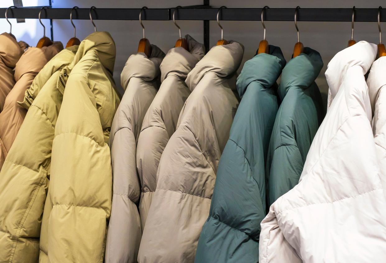 Winter down jackets in various colors hanging on a rack. 