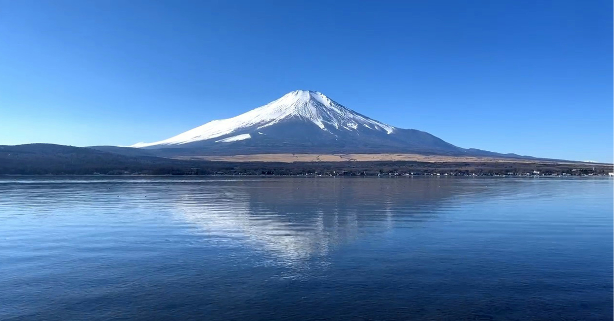 The snowcapped tops of Mt. Fuji are visible across Lake Yamanaka