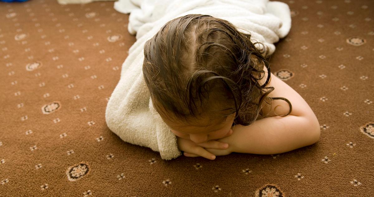 A girl sits on a carpet