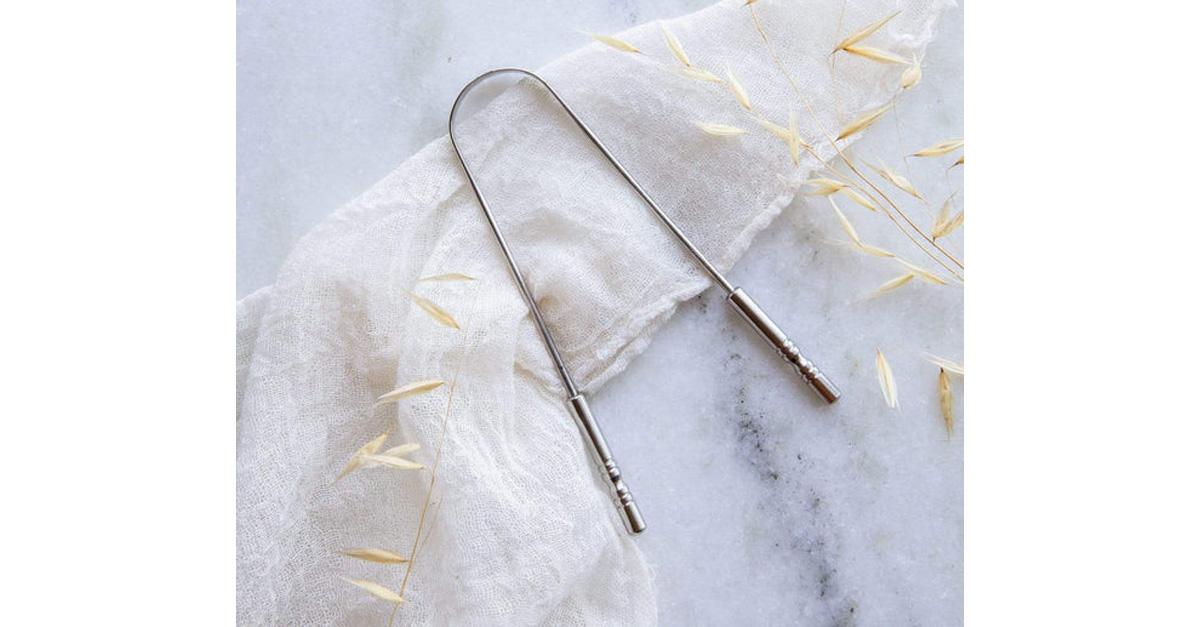 stainless steel tongue scraper on marble surface with cloth