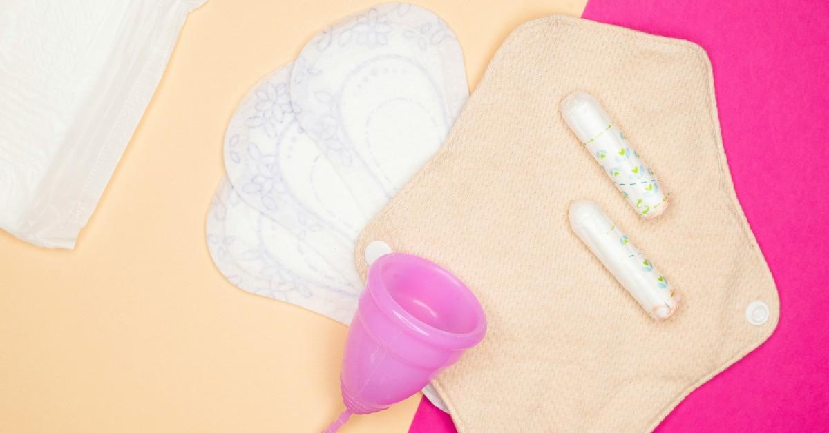 Pads, tampons, and a mensural cup sit on a pink background 
