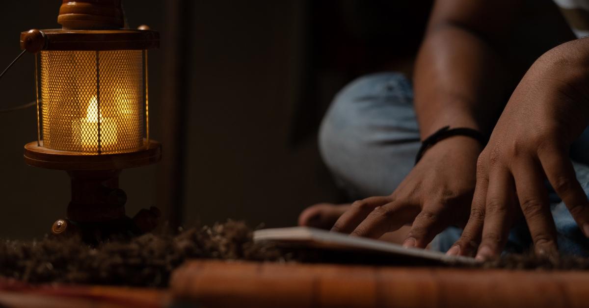 A student studies by the light of an oil lamp in a blackout. 