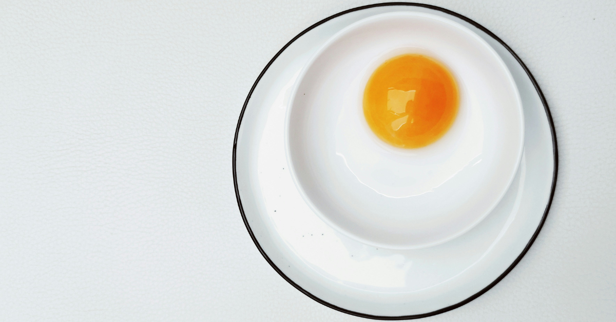 A closeup of an egg yolk in a white bowl on a black and white plate