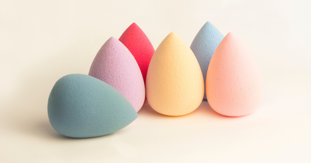 A rainbow assortment of makeup sponges against a pink background