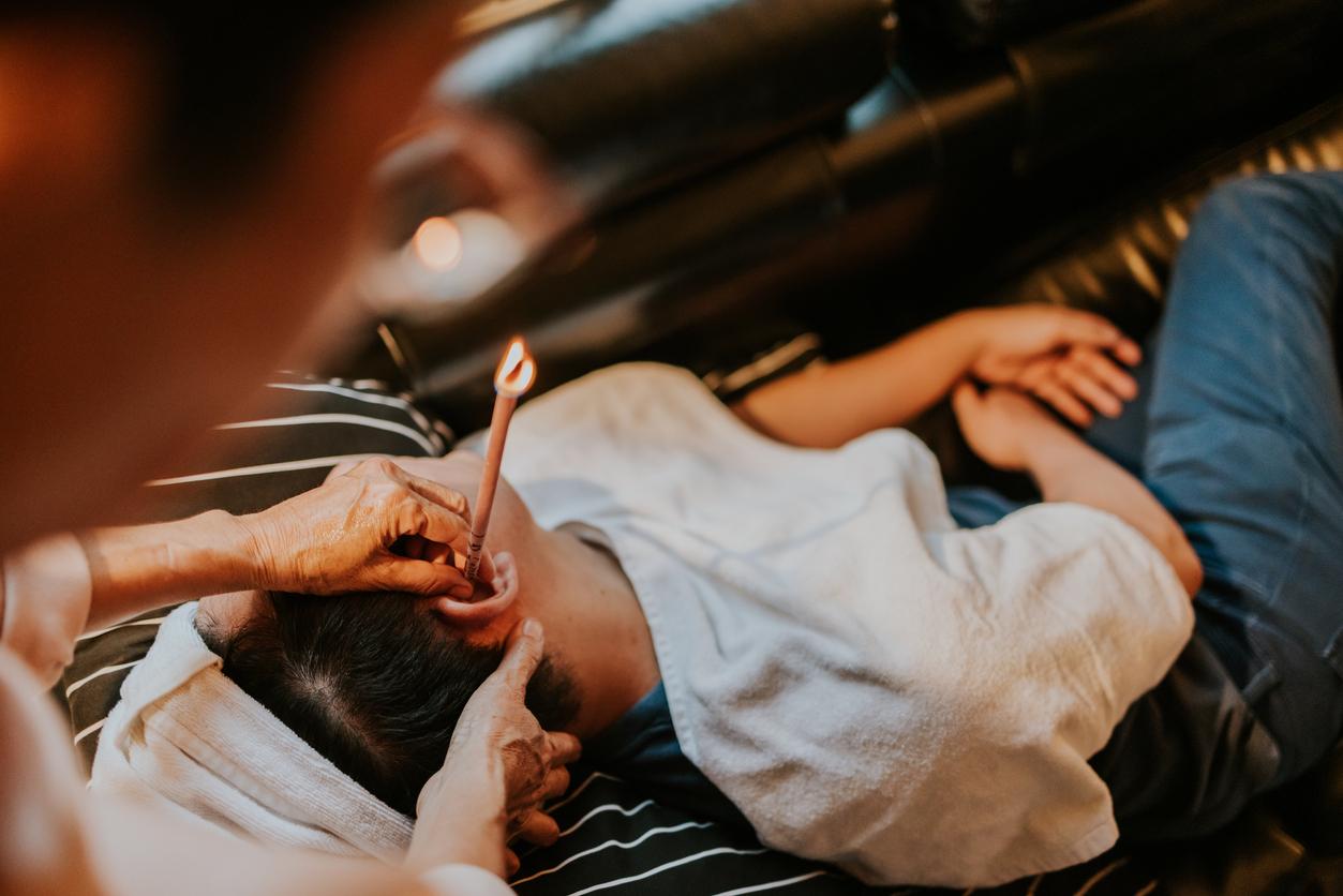 A person at a spa receives ear candling treatment from a spa worker.