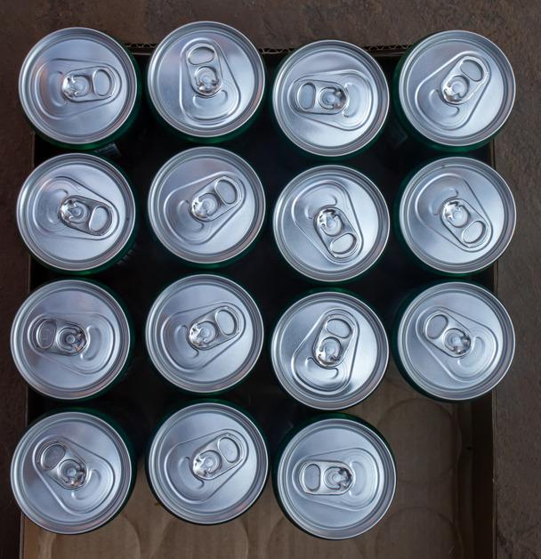 An aerial view of a box containing fifteen aluminum cans. 