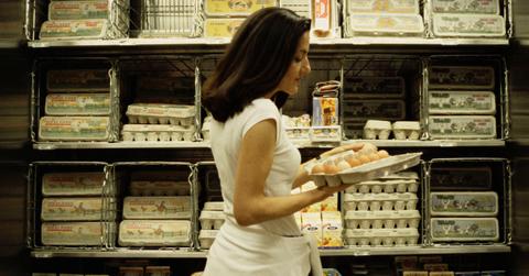 Woman shopping in egg aisle at the grocery store.