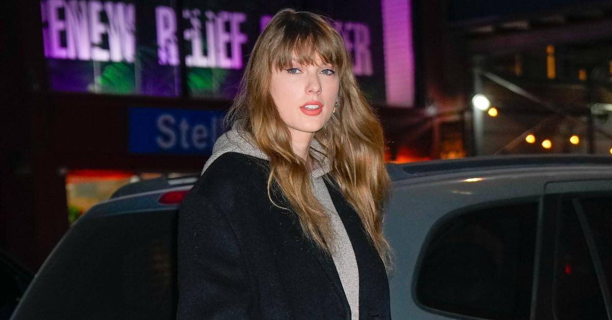 Tayor Swift wears a black coat and a gray hoodie in New York City in 2024.