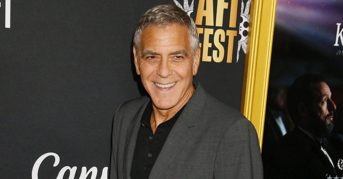 George Clooney smiles while walking the red carpet
