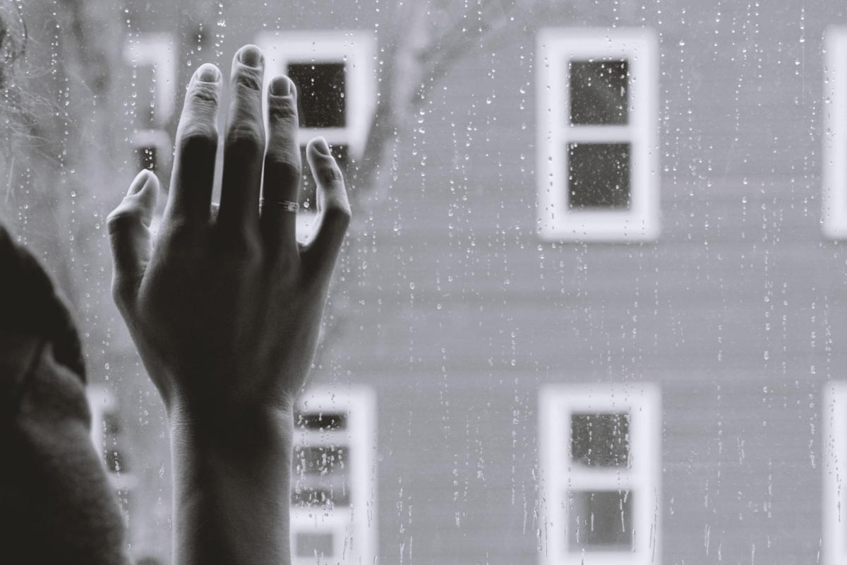 person's right hand touches rainy window