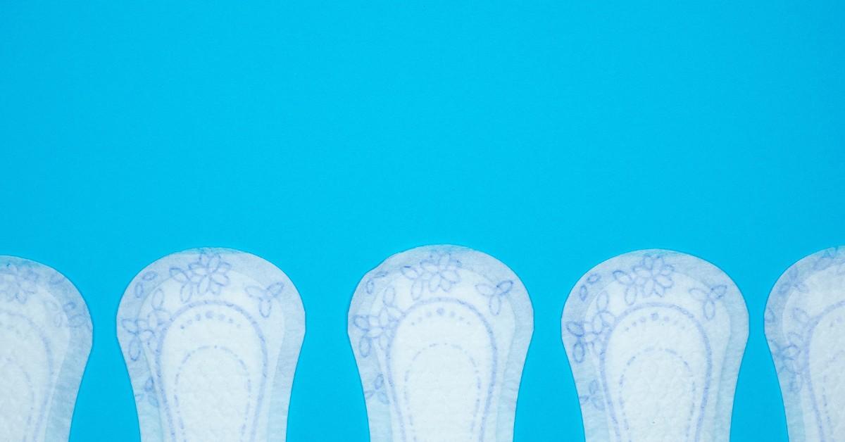 A row of white pantyliners with blue floral desgins on them sits against a blue background