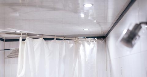 White shower curtain liner hanging on rod in a bathroom