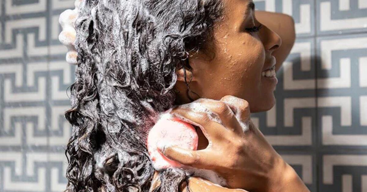 woman washing her hair with a shampoo bar and geometric tiles