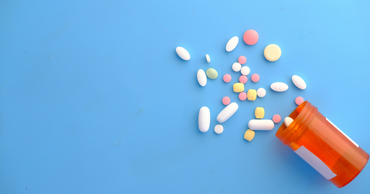 A jar of pills spills out on a blue background