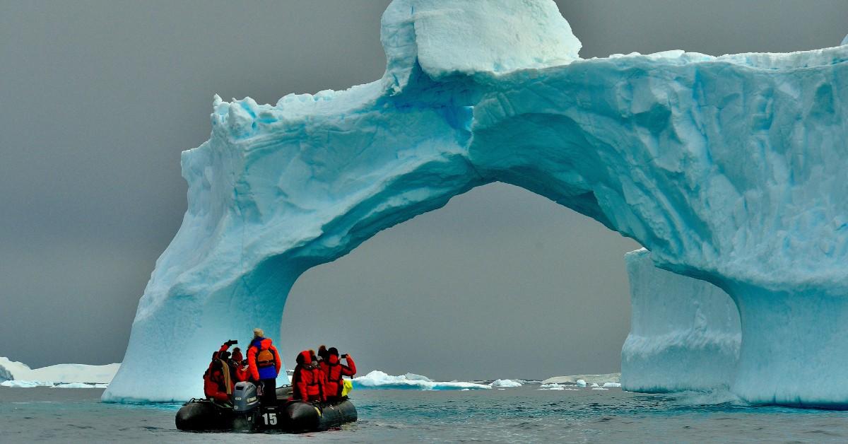 A boat sails towards a glacial arch