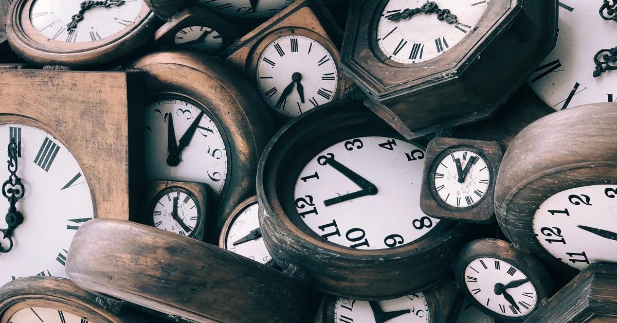 A collection of analogue clocks lay atop one another