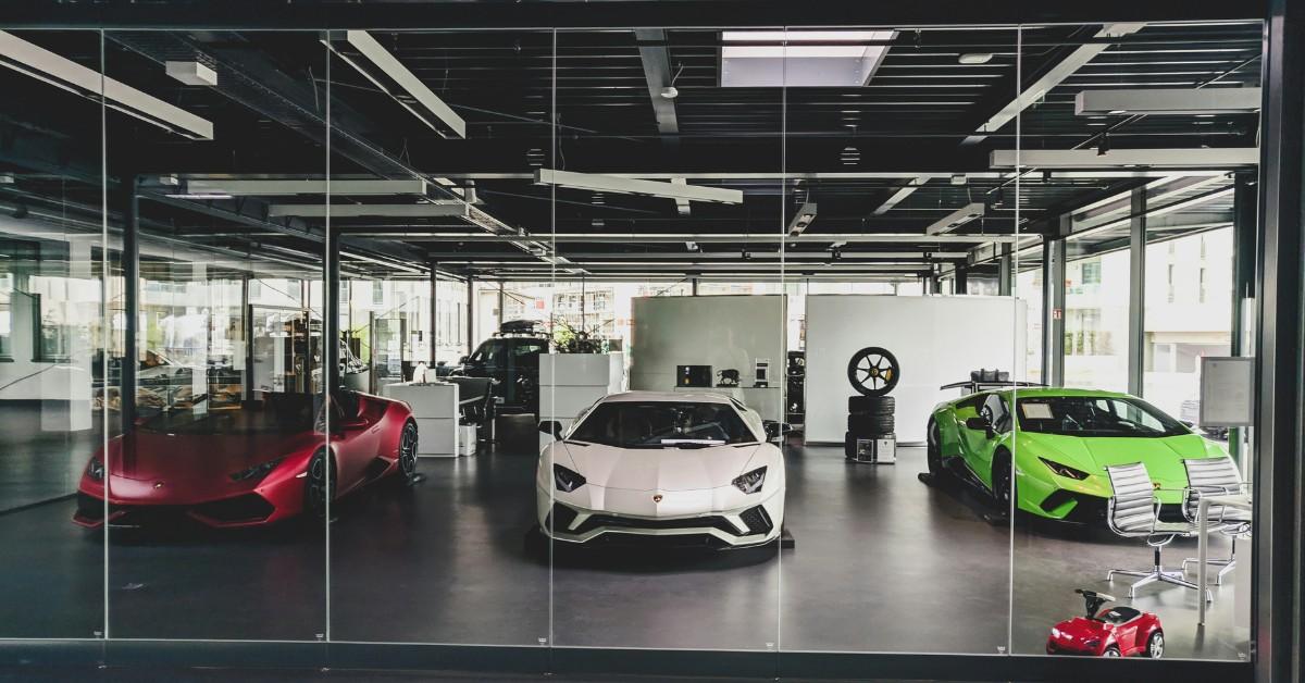 Three cars sit in front of a mirror inside of a car dealership