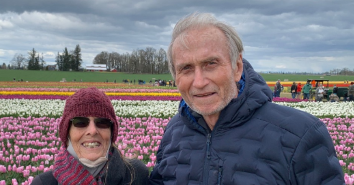 Dr. John McDougall and his wife pose in front of flowers