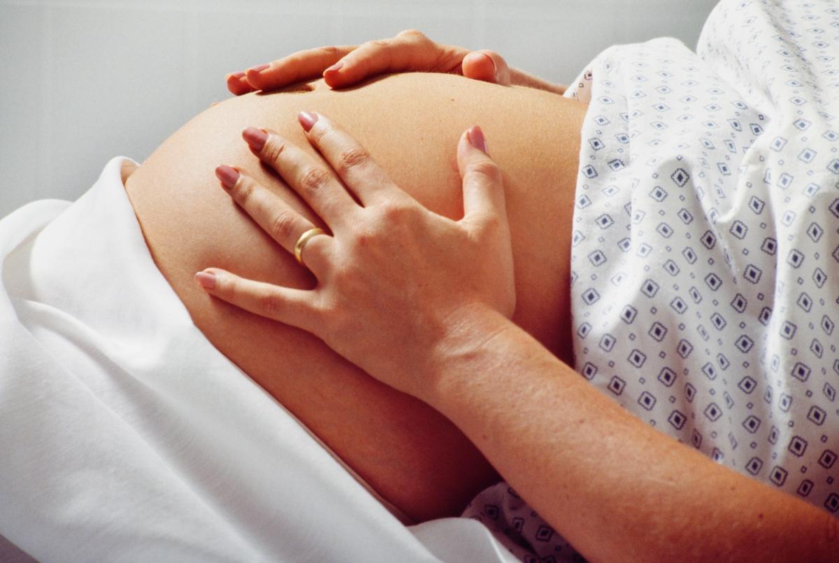 pregnant person in hospital gown with belly exposed