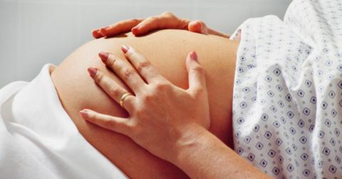 pregnant person in hospital gown with belly exposed