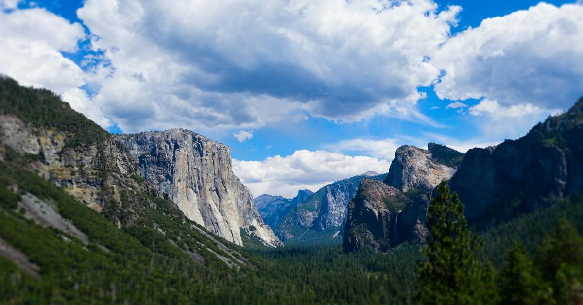 Blue skies and clouds appear behind one of Yosemite National Park's rocky outcrops 